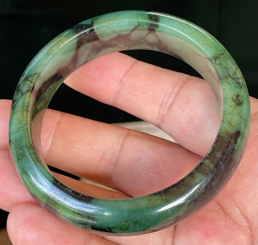 Close-up of fine crystalline texture and deep black tones on icy forest green jadeite bangle