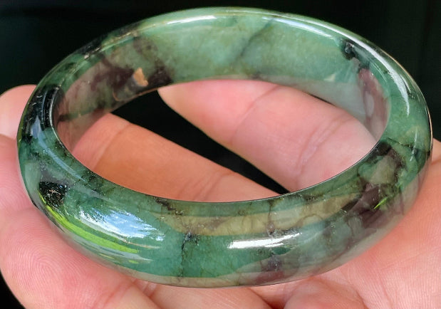 Close-up of fine crystalline texture and deep black tones on icy forest green jadeite bangle