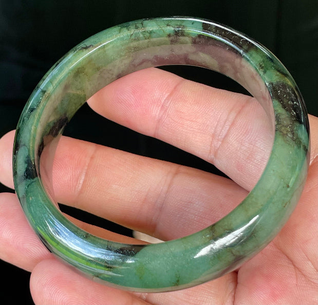 Close-up of fine crystalline texture and deep black tones on icy forest green jadeite bangle