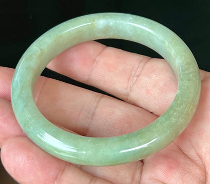 Close-up of fine crystalline texture and subtle cloud-like patterns on icy apple green jadeite bangle
