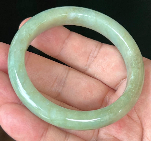 Close-up of fine crystalline texture and subtle cloud-like patterns on icy apple green jadeite bangle