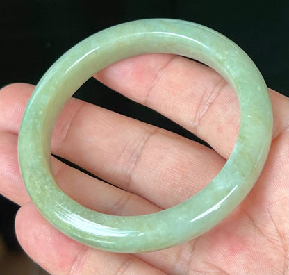 Close-up of fine crystalline texture and subtle cloud-like patterns on icy apple green jadeite bangle
