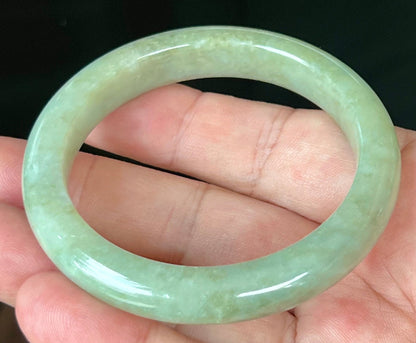 Close-up of fine crystalline texture and subtle cloud-like patterns on icy apple green jadeite bangle