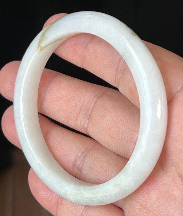 Close-up of fine crystalline texture and forest green hues on icy milky white jadeite bangle