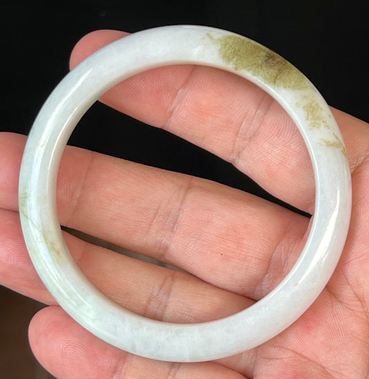 Close-up of fine crystalline texture and forest green hues on icy milky white jadeite bangle