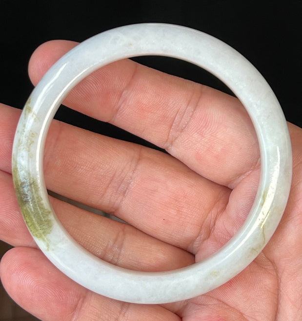 Close-up of fine crystalline texture and forest green hues on icy milky white jadeite bangle