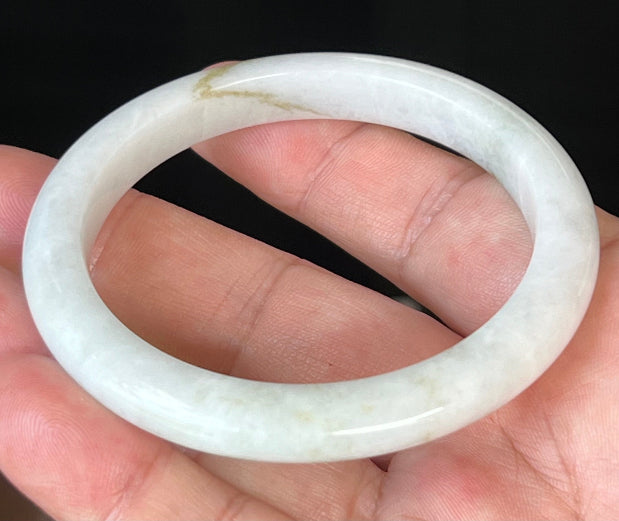 Close-up of fine crystalline texture and forest green hues on icy milky white jadeite bangle