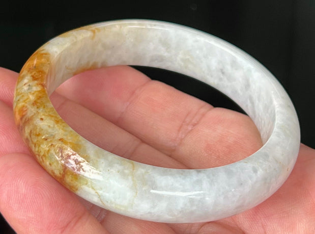 Close-up of fine crystalline texture and vibrant orange red hues on icy greyish white jadeite bangle