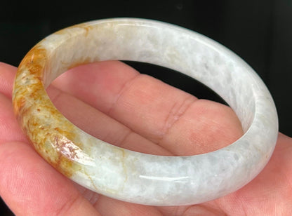 Close-up of fine crystalline texture and vibrant orange red hues on icy greyish white jadeite bangle