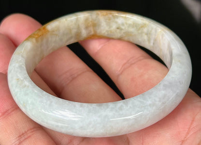 Close-up of fine crystalline texture and vibrant orange red hues on icy greyish white jadeite bangle