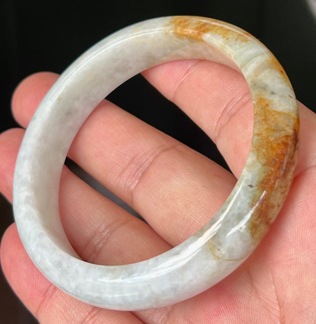 Close-up of fine crystalline texture and vibrant orange red hues on icy greyish white jadeite bangle