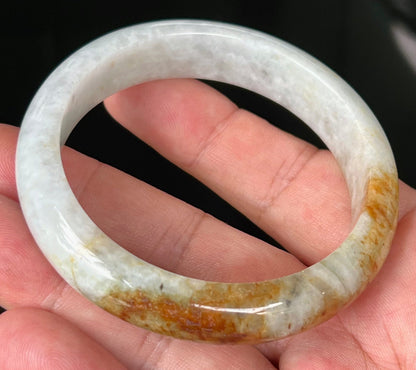 Close-up of fine crystalline texture and vibrant orange red hues on icy greyish white jadeite bangle