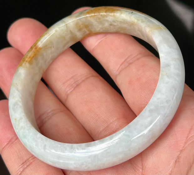 Close-up of fine crystalline texture and vibrant orange red hues on icy greyish white jadeite bangle