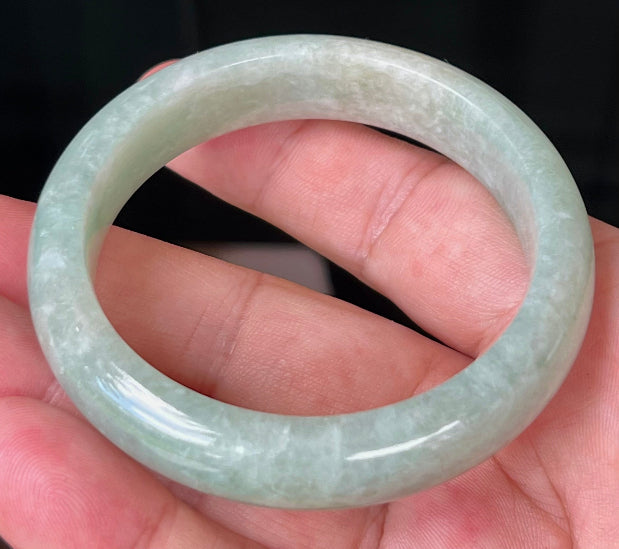 Close-up of fine crystalline texture and milky white tones on icy apple green jadeite bangle