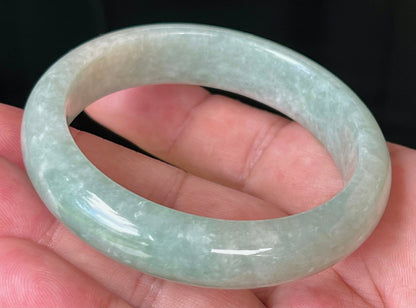 Close-up of fine crystalline texture and milky white tones on icy apple green jadeite bangle