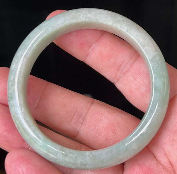 Close-up of fine crystalline texture and milky white tones on icy apple green jadeite bangle