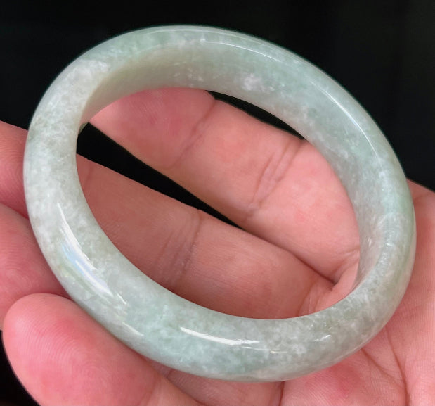 Close-up of fine crystalline texture and milky white tones on icy apple green jadeite bangle