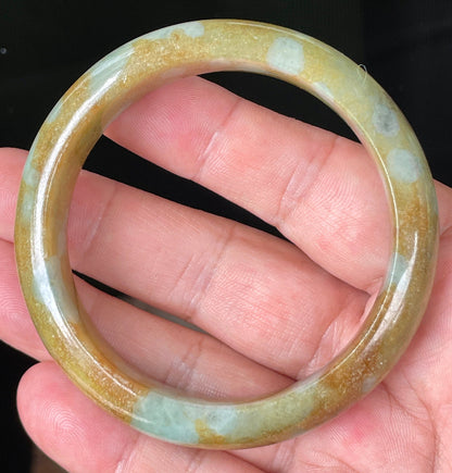 Close-up of fine crystalline texture and warm honey brown tones on bluish milky white jadeite bangle
