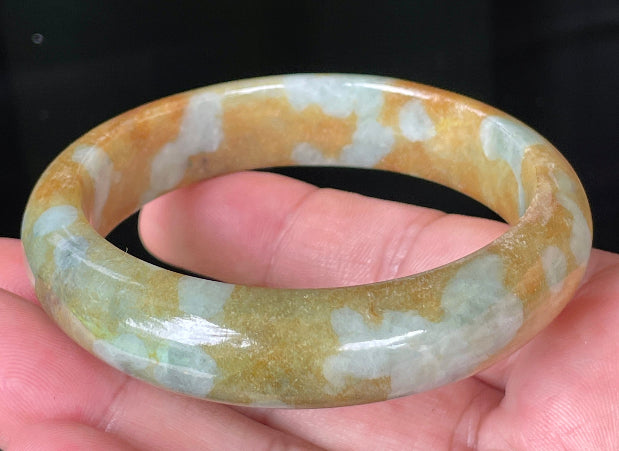 Close-up of fine crystalline texture and warm honey brown tones on bluish milky white jadeite bangle