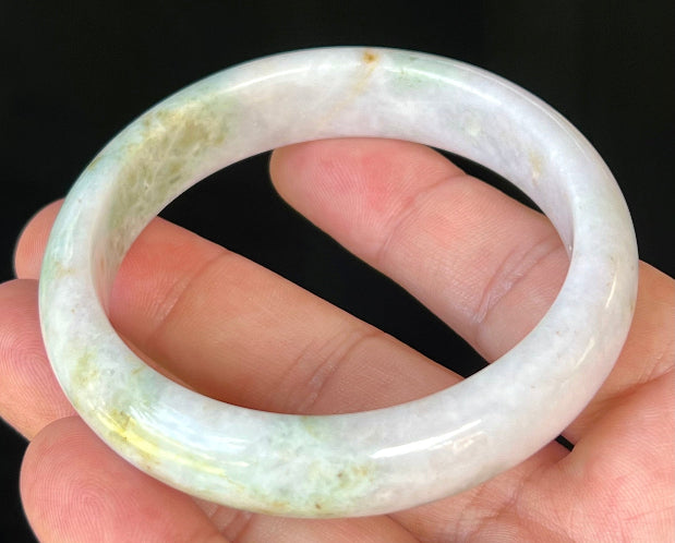 Close-up of fine crystalline texture and forest green streaks on icy milky white jadeite bangle