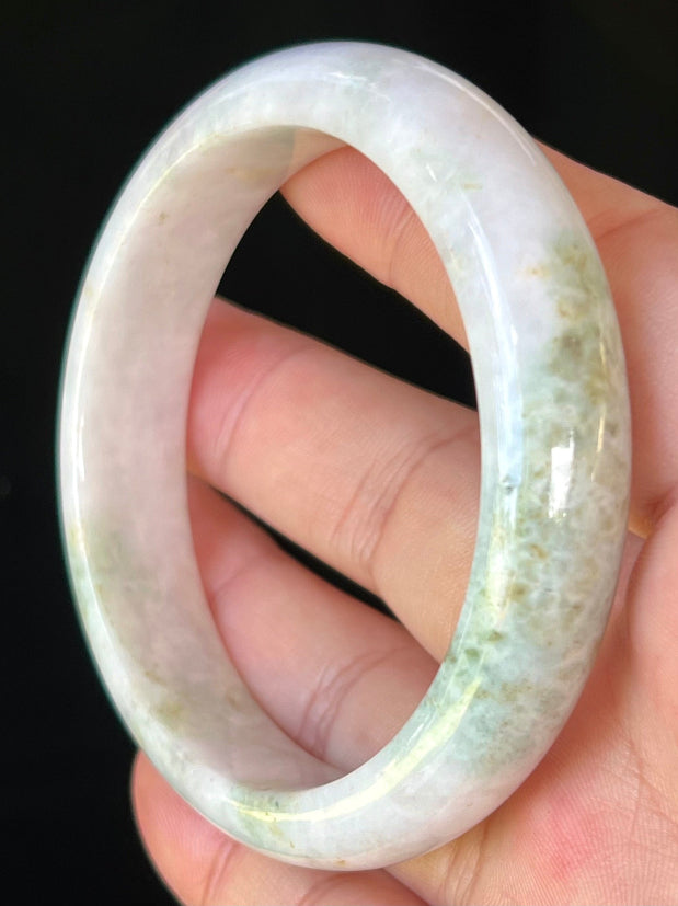 Close-up of fine crystalline texture and forest green streaks on icy milky white jadeite bangle