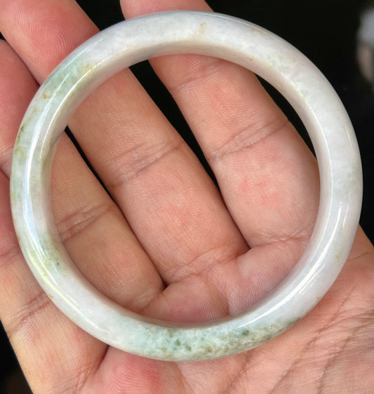 Close-up of fine crystalline texture and forest green streaks on icy milky white jadeite bangle