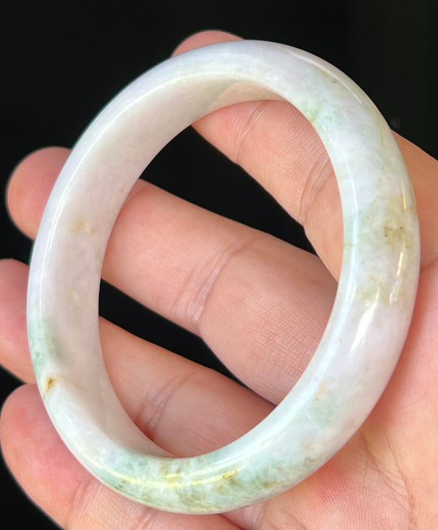 Close-up of fine crystalline texture and forest green streaks on icy milky white jadeite bangle
