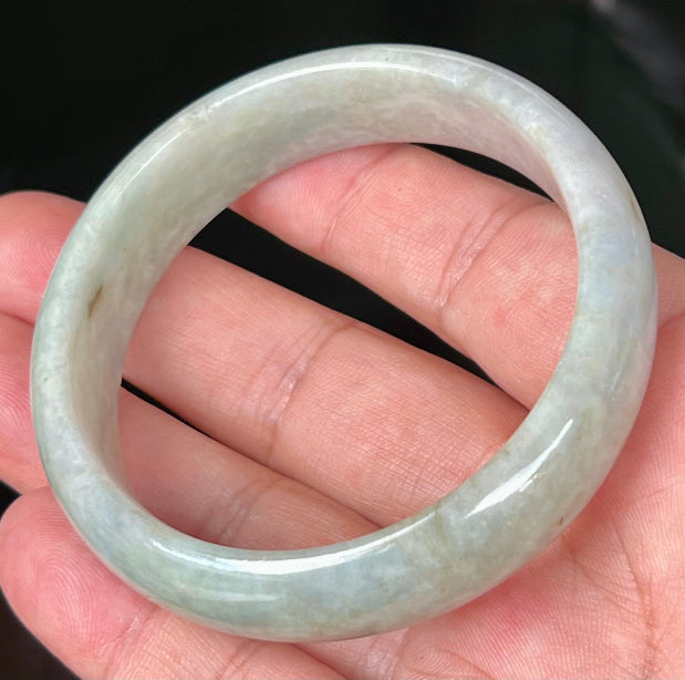 Close-up of fine crystalline texture and greyish hues on icy apple green jadeite bangle