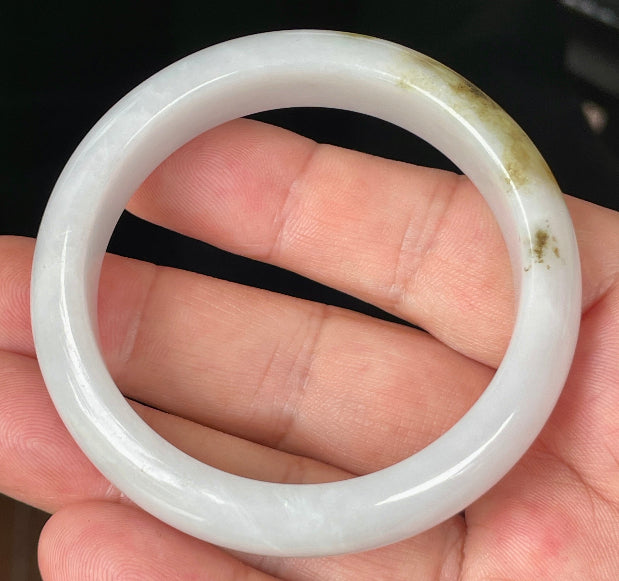 Close-up of fine crystalline texture and refreshing apple green swirls on icy milky white jadeite bangle