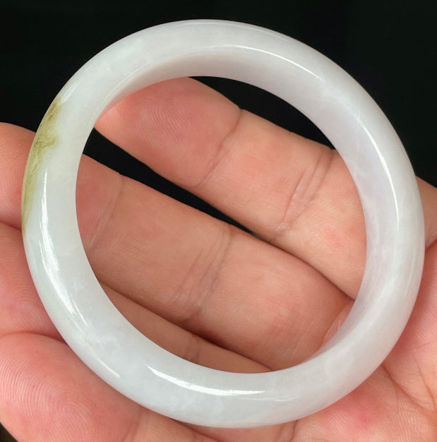 Close-up of fine crystalline texture and refreshing apple green swirls on icy milky white jadeite bangle
