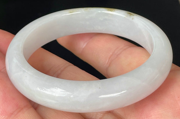Close-up of fine crystalline texture and refreshing apple green swirls on icy milky white jadeite bangle