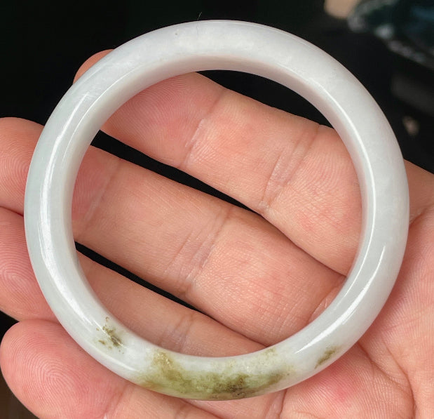 Close-up of fine crystalline texture and refreshing apple green swirls on icy milky white jadeite bangle