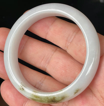 Close-up of fine crystalline texture and refreshing apple green swirls on icy milky white jadeite bangle