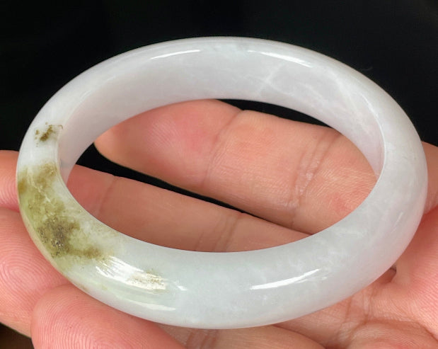 Close-up of fine crystalline texture and refreshing apple green swirls on icy milky white jadeite bangle