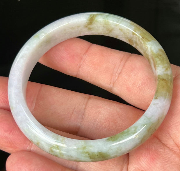 Close-up of fine crystalline texture and light brown hues on icy milky white jadeite bangle