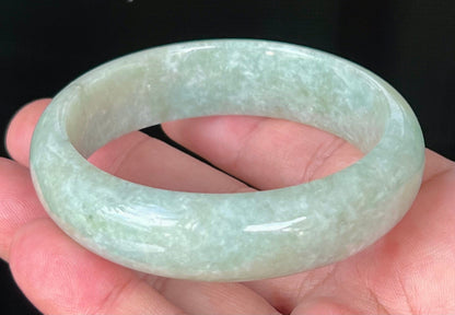 Close-up of fine crystalline texture and milky white hues on icy light apple green jadeite bangle