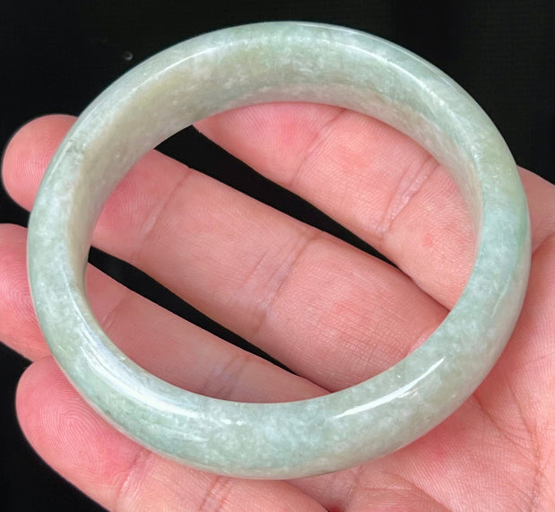 Close-up of fine crystalline texture and milky white hues on icy light apple green jadeite bangle