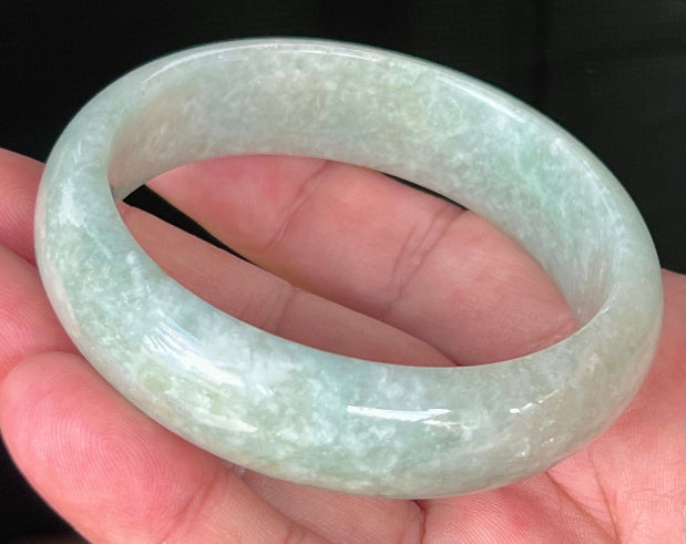 Close-up of fine crystalline texture and milky white hues on icy light apple green jadeite bangle