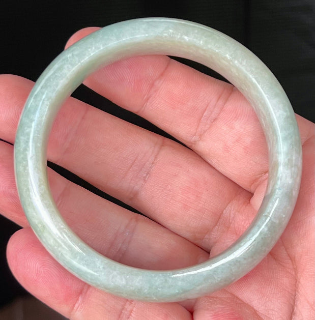 Close-up of fine crystalline texture and milky white hues on icy light apple green jadeite bangle