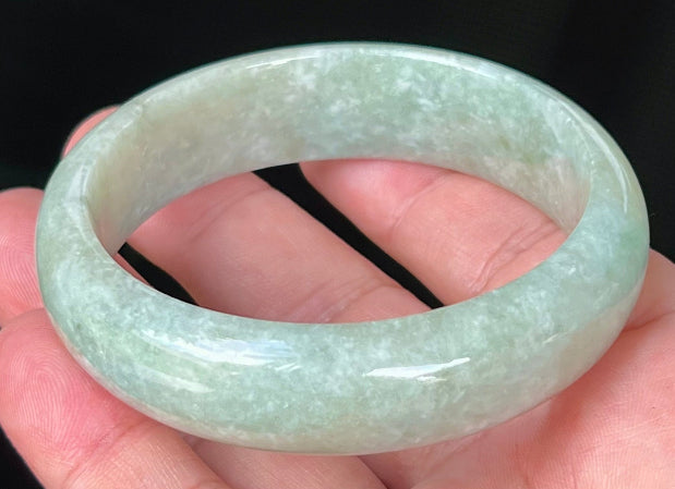 Close-up of fine crystalline texture and milky white hues on icy light apple green jadeite bangle