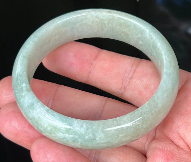Close-up of fine crystalline texture and milky white hues on icy light apple green jadeite bangle