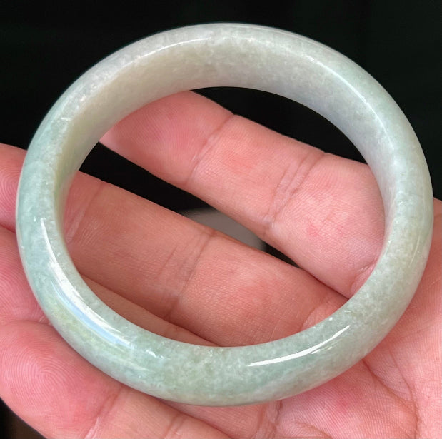 Close-up of fine crystalline texture and milky white hues on icy apple green jadeite bangle