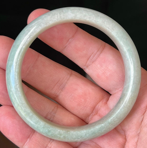 Close-up of fine crystalline texture and milky white hues on icy apple green jadeite bangle