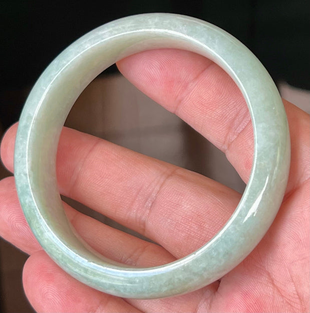 Close-up of fine crystalline texture and milky white hues on icy apple green jadeite bangle