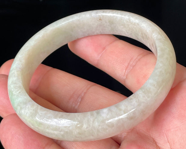 Close-up of fine crystalline texture and light imperial green hues on icy honey and white jadeite bangle