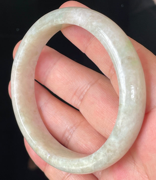 Close-up of fine crystalline texture and light imperial green hues on icy honey and white jadeite bangle