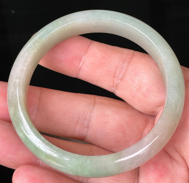 Close-up of fine crystalline texture and vibrant apple green hues on milky white jadeite bangle