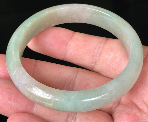 Close-up of fine crystalline texture and vibrant apple green hues on milky white jadeite bangle