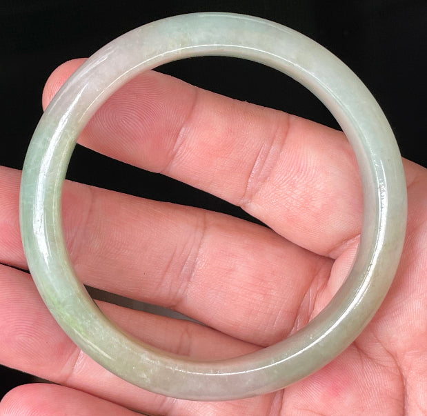 Close-up of fine crystalline texture and vibrant apple green hues on milky white jadeite bangle