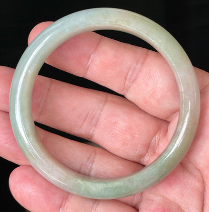 Close-up of fine crystalline texture and vibrant apple green hues on milky white jadeite bangle